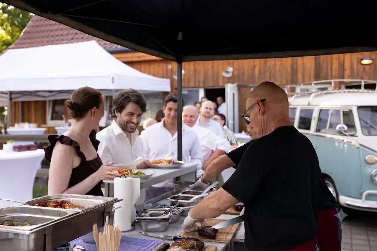 Hochzeitsgäste stehen am Grillbuffet an