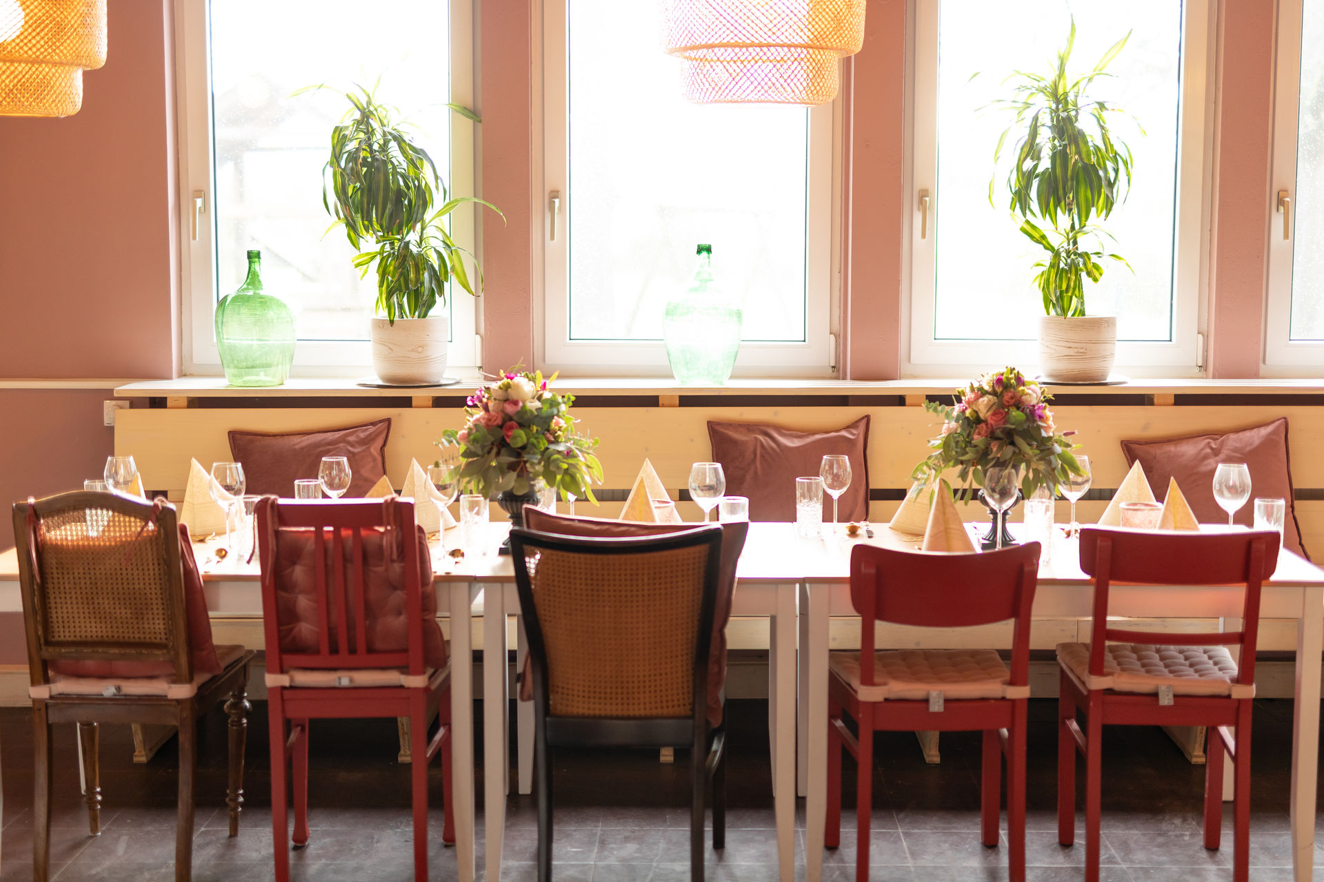 festlich eingedeckter Tisch mit Blumen an der sonnigen Fensterfront