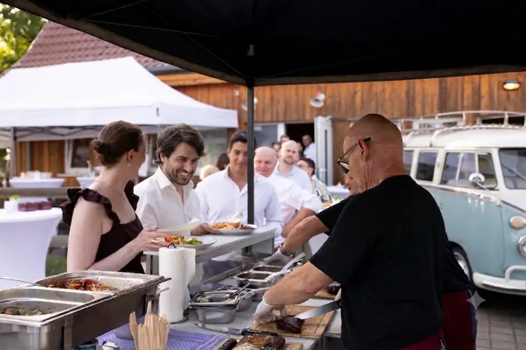 Hochzeitsgäste stehen am Grillbuffet an