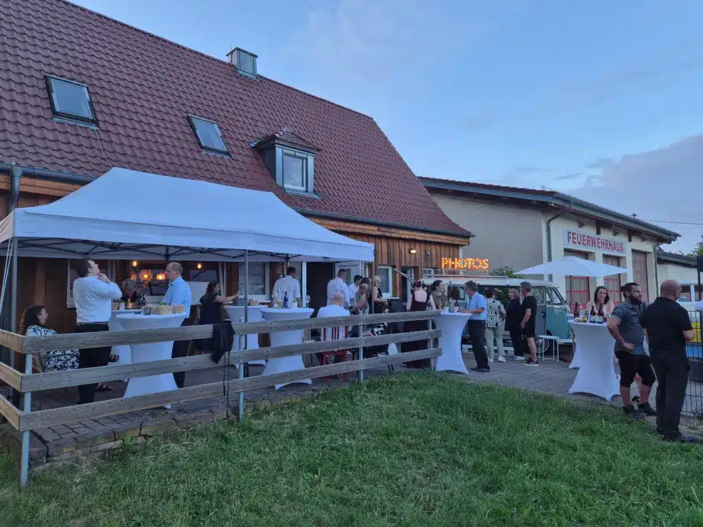 Gäste genießen die Abendstimmung unter dem Pavillon und dem Photobulli auf der Terrasse